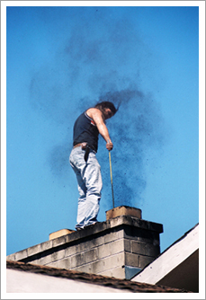Young man standing on the roof of the house,cleaning the chimney